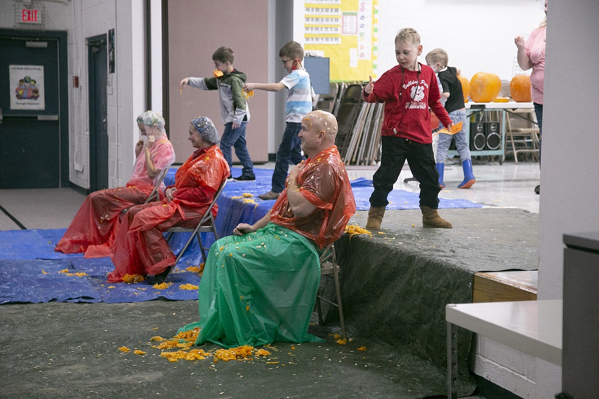 From front, Superintendent Paul Anselmo, sixth grade teacher Wilma Hahn, and Principal Susie Luckey sit in the auditorium at Idaho Hill Elementary School while students, and some teachers, throw "pumpkin guts" on them as a reward for hitting their reading quota for the fall quarter.