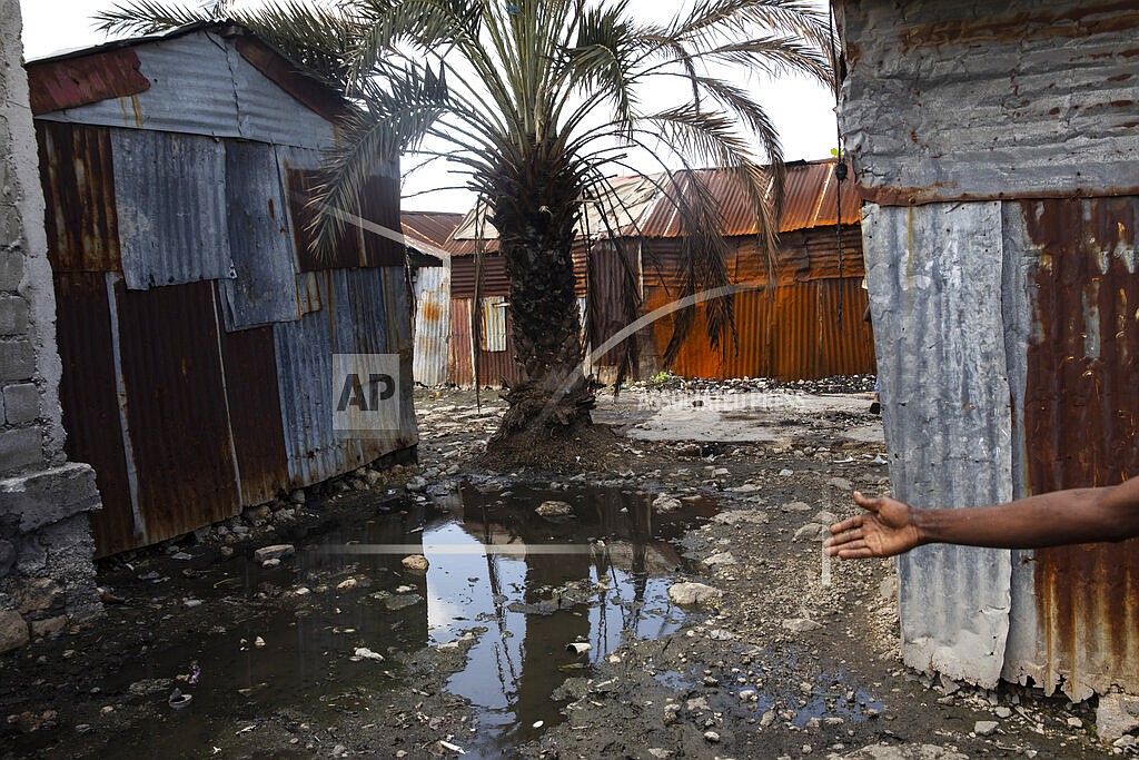 A neighbor describes the poverty in which she lives in outside her house built with recycled metal sheets, in the Cite Soleil shanty town of Port-au-Prince, Haiti, Friday, Oct. 1, 2021. (AP Photo/Rodrigo Abd)