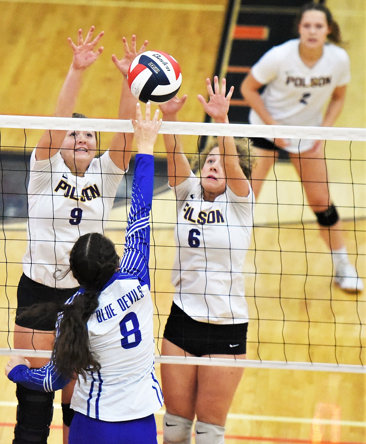 Clara Todd (9) and Camilla Foresti (6) rise to block a shot by Olivia Lewis of Corvallis. (Scot Heisel/Lake County Leader)