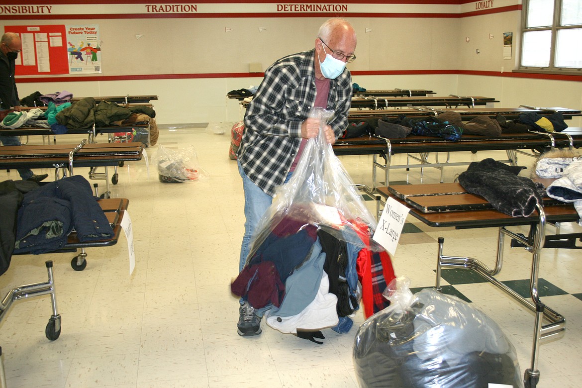 Moses Lake Rotary Club member Dave Campbell opens a bag of coats ready for sorting during Friday setup for the annual Coats 4 Kids distribution.