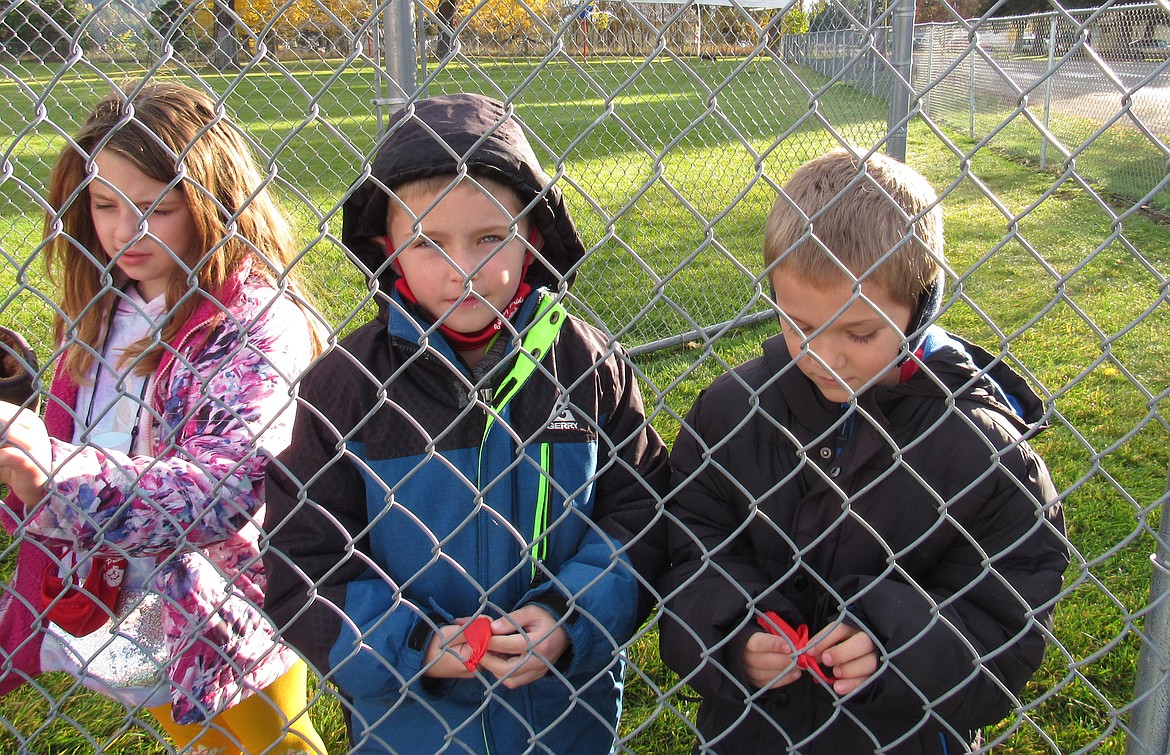 A trio of students weave red ribbons into the fence around Idaho Hill Elementary to celebrate Red Ribbon Week in late October.