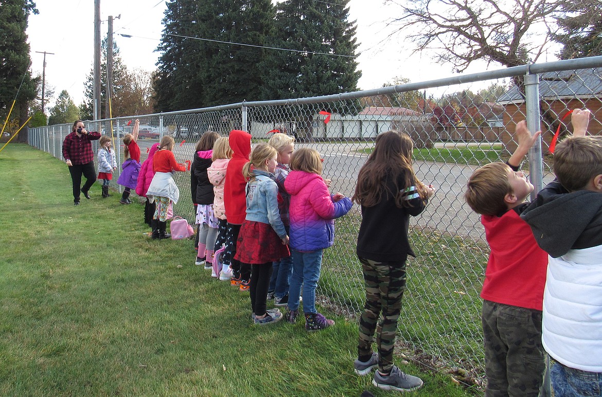 Idaho Hill Elementary students weave red ribbons into the school's chainlink fence in honor of Red Ribbon Week.