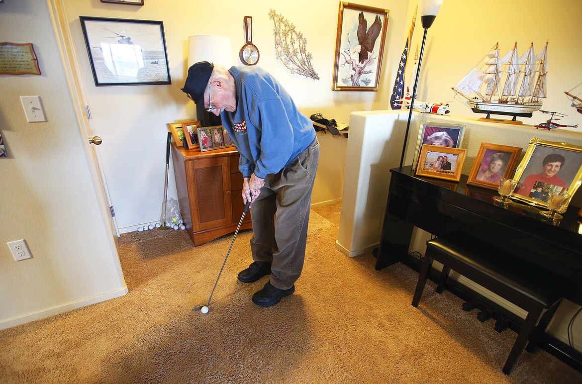 Earl Carroll practices putting in the living room of his home on Wednesday.