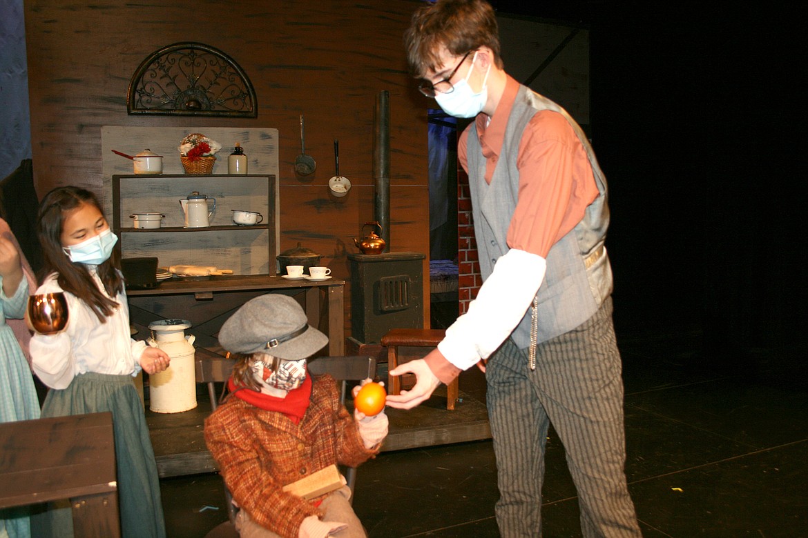 Bob Cratchit (Cody Kennedy, right) gives his Tiny Tim (Krysandra Coyle, left) a Christmas orange in the Quincy High School production of “A Christmas Carol.”