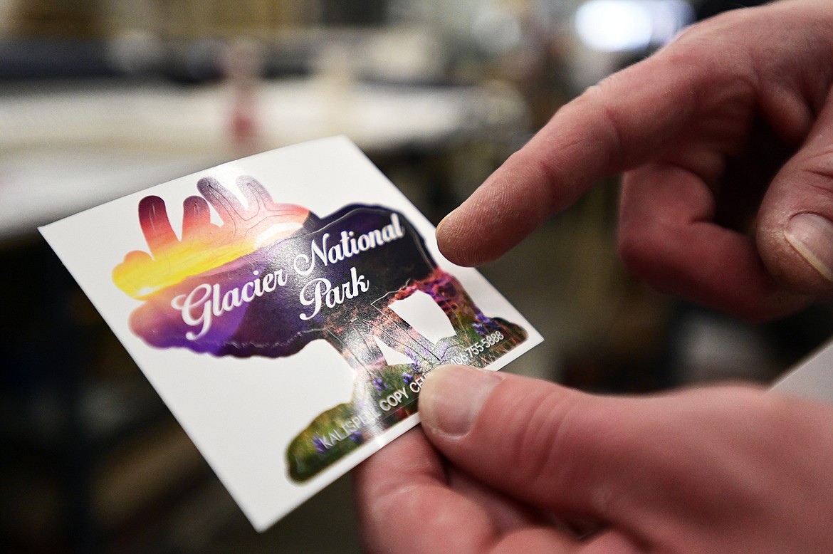 Anthoney Zollman, with Kalispell Copy Center, holds an example of a glossy, pre-cut sticker printed on the company’s solvent-based inkjet printer on Thursday, Nov. 11. (Casey Kreider/Daily Inter Lake)