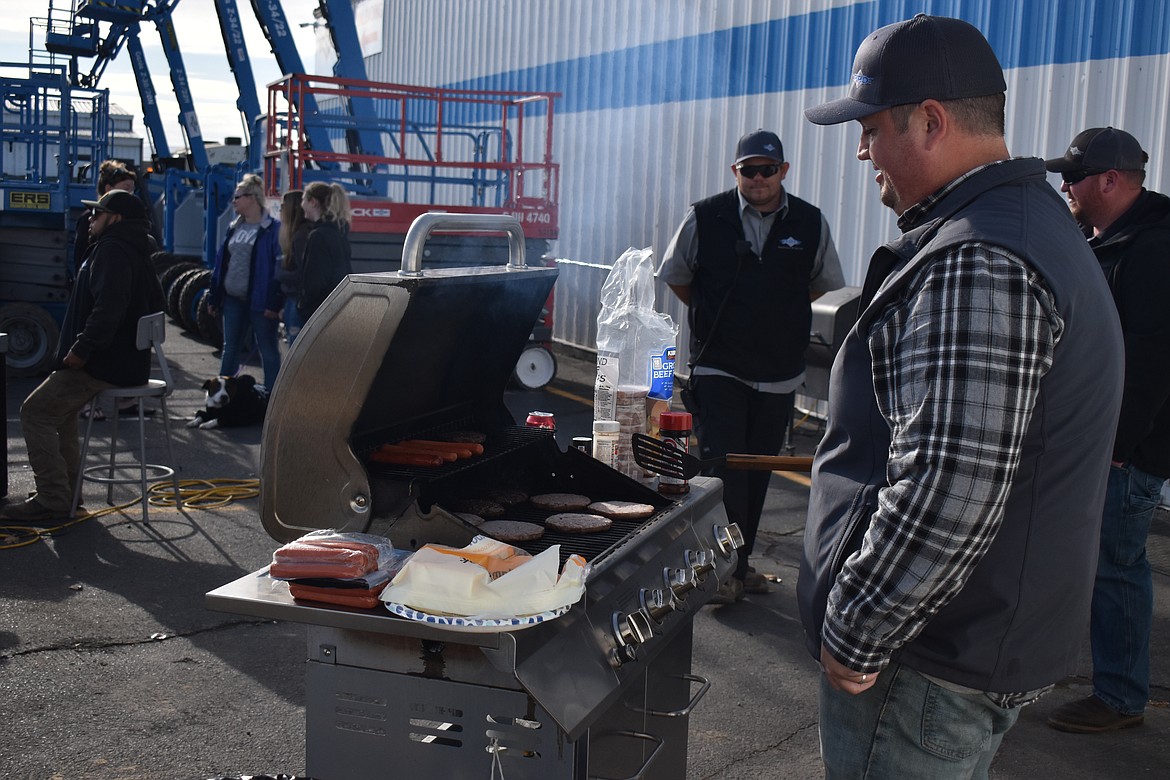 Jared Brown cooks burgers and hot dogs on the grill on Wednesday during the fundraiser for an employee whose house burned down in October.