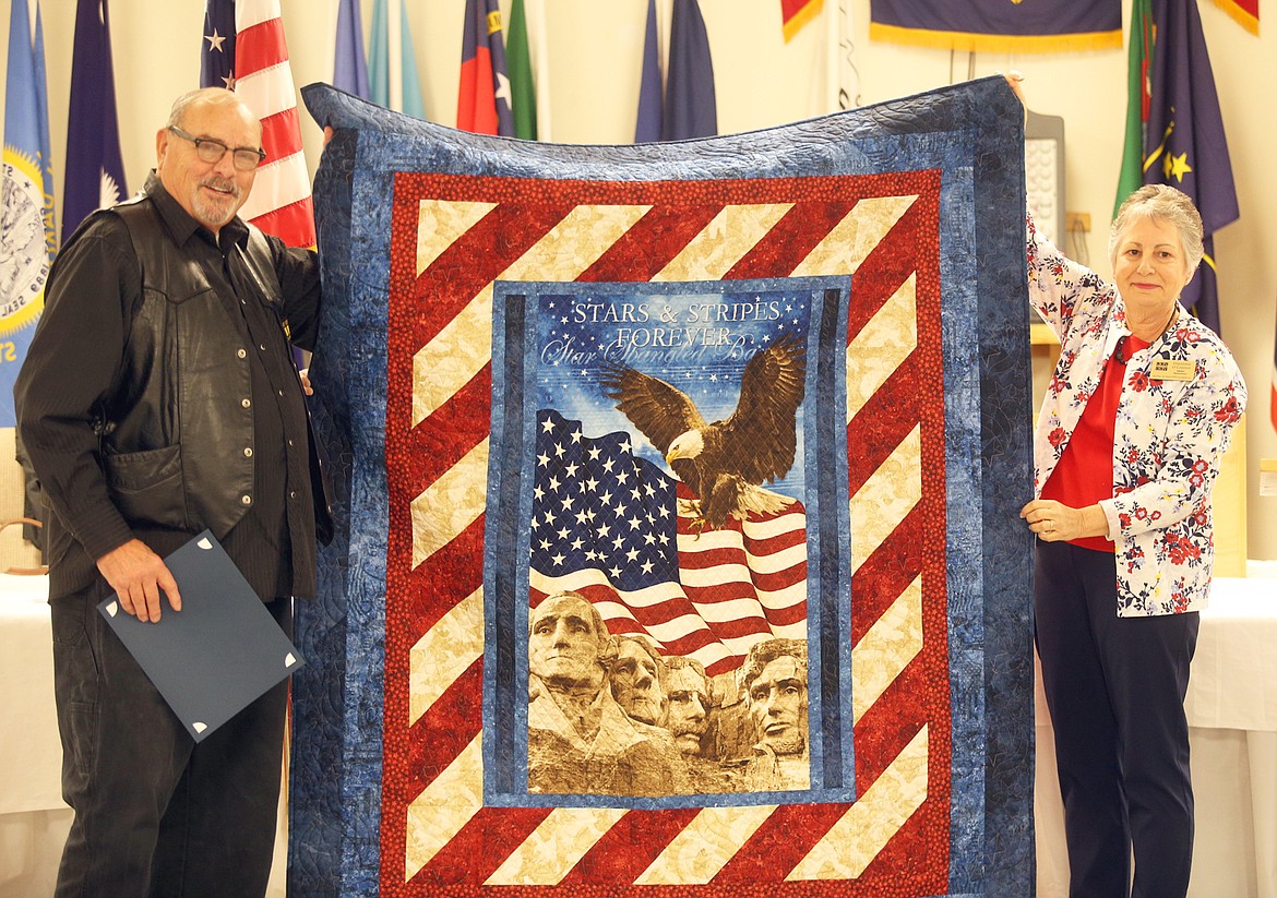 Veteran Stan Rogers of Post Falls holds up his Quilt of Valor with help from Giannine O’Connor of the Patriotic Piecers at the American Legion in Post Falls on Thursday.