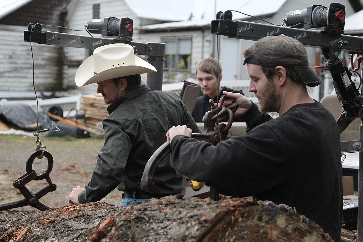 Josh Byers, left, Sean Byers and Jon Byers load a log onto the converted Ford Bronco. (Will Langhorne/The Western News)