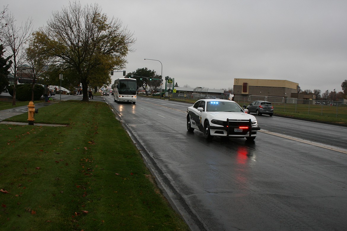 A deputy in a car from the Grant County Sheriff’s Office escorts the Moses Lake High School football team out of town on Pioneer Way toward Interstate 90 to the team's first state playoff game since 2017.