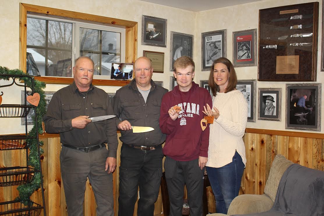 The Hangas family, owners of Ruana Knives, displays their wares. Mark displays a new Damascus blade while Mike holds the knife that should be in a scene of “Yellowstone” this season. Jack is holding a leather keychain of the state of Montana and Kirsten is showing some of their Christmas ornaments. Seamus is just happy to be with them. (Monte Turner/Mineral Independent)