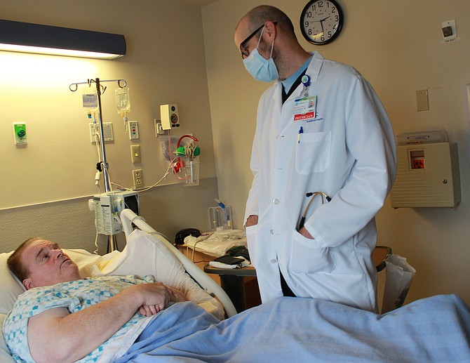 Kootenai Health hospitalist John Siemers, M.D., checks on patient Ray Hoyt in October as Hoyt undergoes treatment for an infection.
