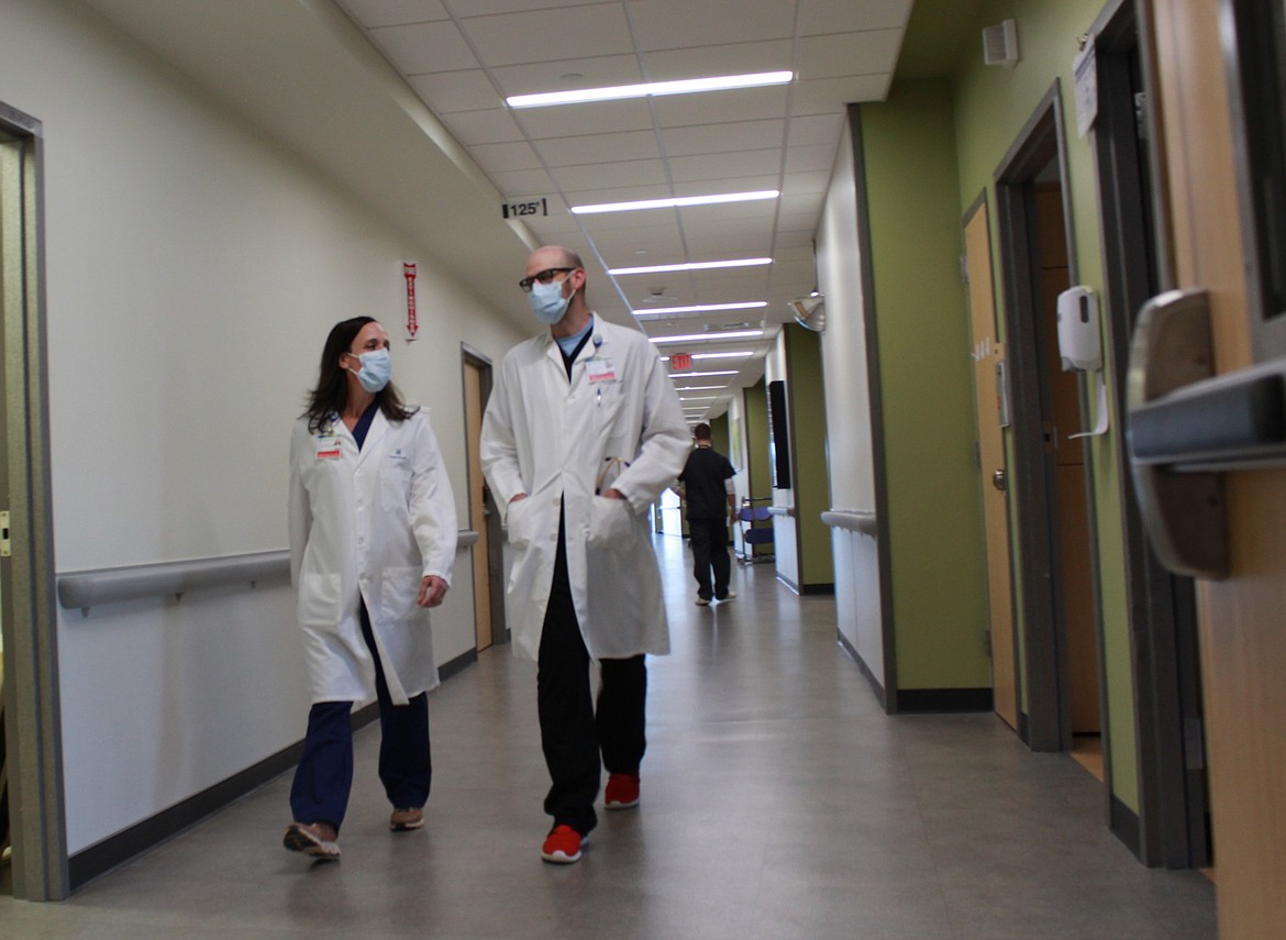 Drs. Maggie Greene and John Siemers talk while they walk along a second-floor hallway in Kootenai Health. Greene and Siemers are two of nearly 20 hospitalists who dedicate their work to adult patients in the hospital.