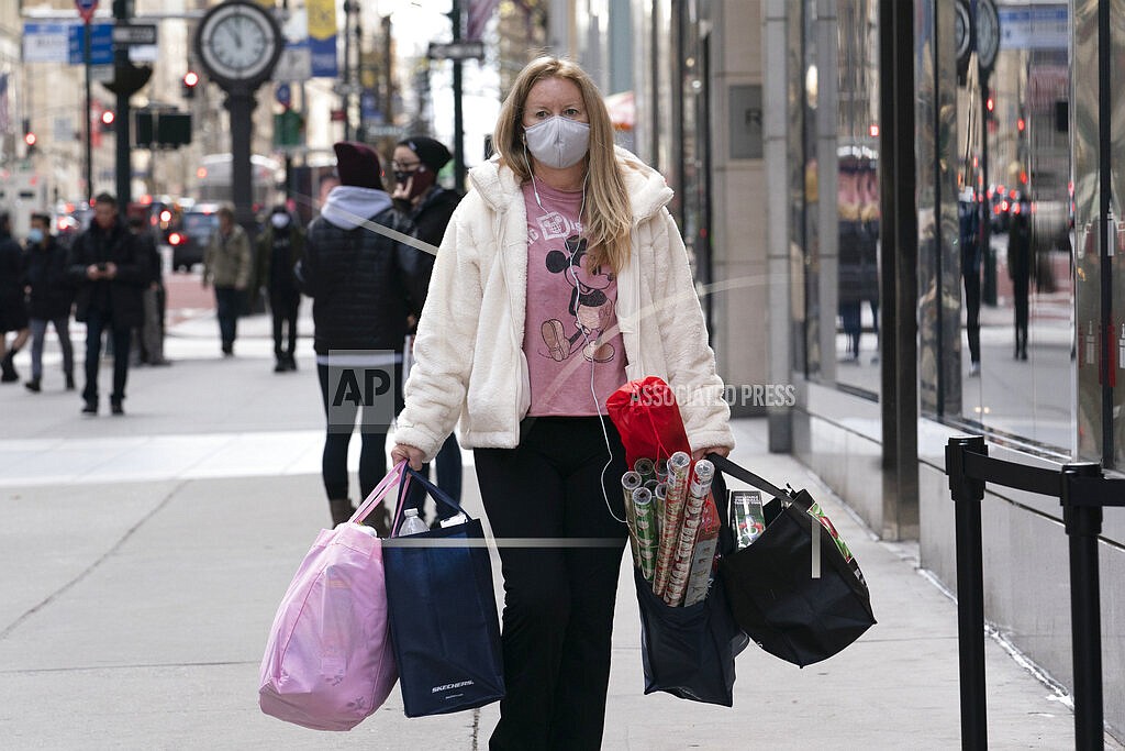 In this Dec. 10, 2020 file photo, a woman carries shopping bags in New York. The National Retail Federation expects that holiday sales gain could shatter last year’s record-breaking season even as a snarled global supply chain slows the flow of goods and results in higher prices for broad range of items. The nation's largest retail trade group said Wednesday, Oct. 27, 2021 it predicts that sales for the November and December period will grow between 8.5% and 10.5% to $843.4 billion and $859 billion. (AP Photo/Mark Lennihan, File)