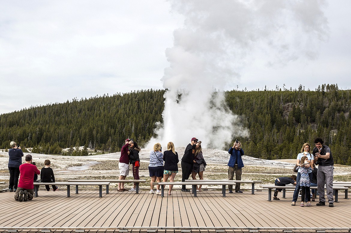 Visitors watch as Old Faithful erupts at Yellowstone National Park, Wyo.