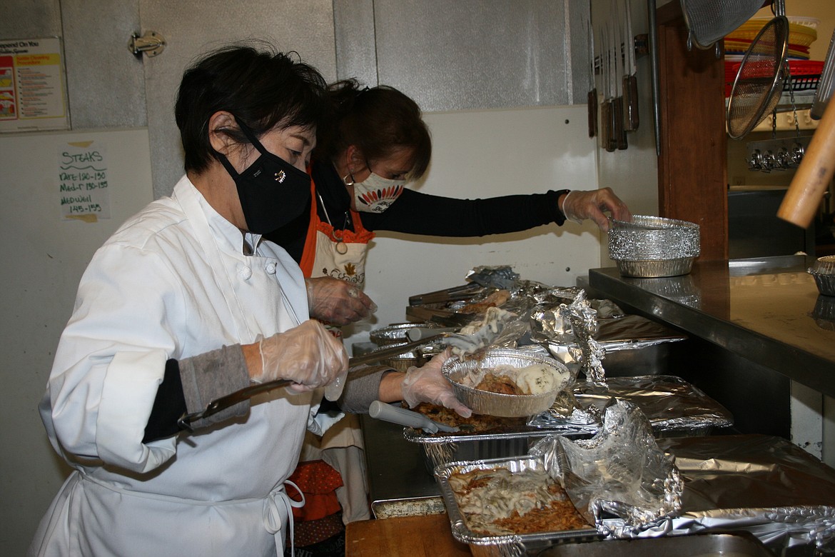 Columbia Basin Job Corps Civilian Conservation Center culinary instructors Minae Suetsugu (front) and Theresa Clement (back) prepare plates during the annual community Thanksgiving dinner Wednesday.