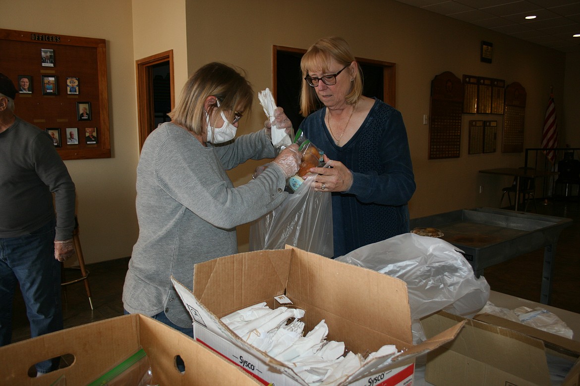 Jennifer Killian, left, and Vicky Rutherford prepare dinner for delivery during the community Thanksgiving dinner Wednesday.