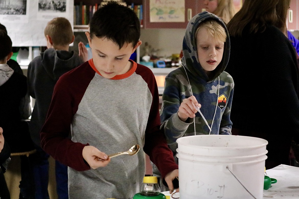 From left, fourth graders Rome Castro-Muelhausen and Jonah Halone experiment with Fernan Lake water at the Idaho live history day Wednesday at Fernan STEM Academy. HANNAH NEFF/Press