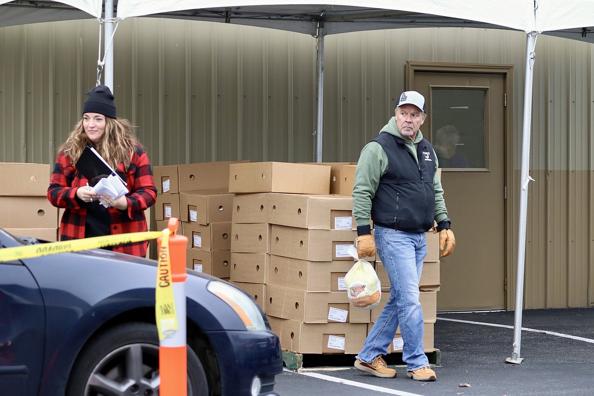 From left, standing in front of pallets staked high with boxes of frozen turkeys, Ada Rouse and Kelly Glenn help with distribution for Turkeys and More at Heart of the City Church in Coeur d'Alene on Thursday. The group gave away around 650 turkeys and Super 1 Foods gift cards at the church, equalling 1,800 birds given away including the ones distributed through food banks. HANNAH NEFF/Press