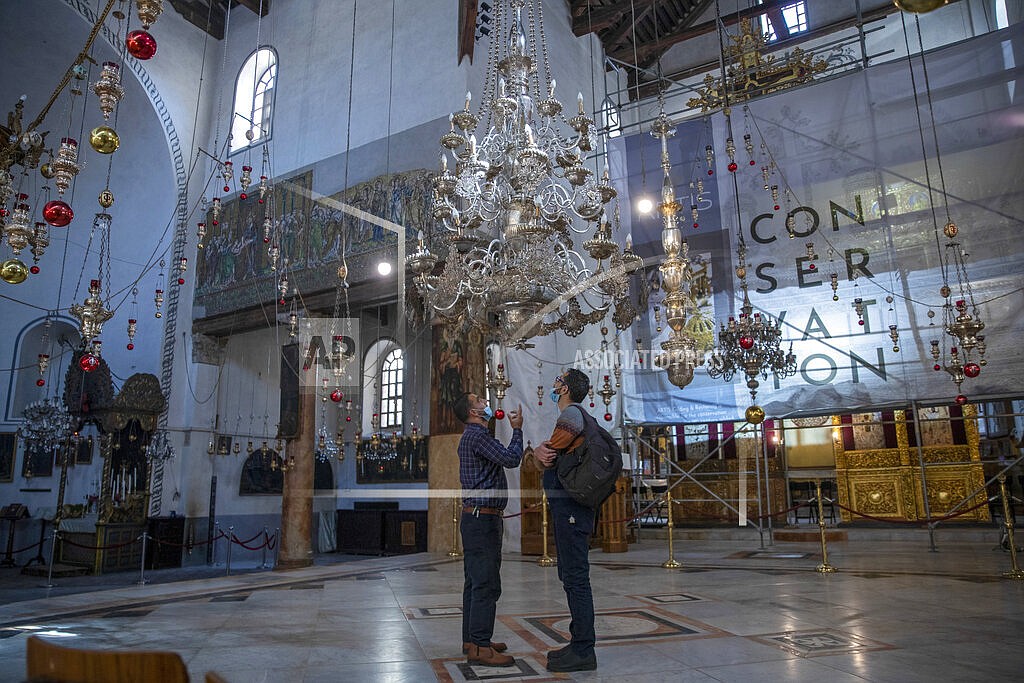 Tourists visit the Church of the Nativity, in the West Bank city of Bethlehem, Tuesday, Nov. 16, 2021. The Church of the Nativity, built on the spot where Christians believe Jesus was born, is wrapping up a three-year restoration project just in time for the normally busy Christmas season. While the region is finally welcoming foreign tourists after a year-and-a-half-long COVID shutdown, few travelers are making their way to the birthplace of Jesus this holiday season (AP Photo/Nasser Nasser)