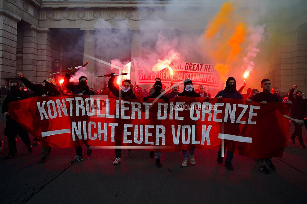 Demonstrators shout slogans and light flares during a demonstration against measures to battle the coronavirus pandemic in Vienna, Austria, Saturday, Nov. 20, 2021. Thousands of protesters are expected to gather in Vienna after the Austrian government announced a nationwide lockdown to contain the quickly rising coronavirus infections in the country. Banner reads: ' Controls the border. Not your people'. (AP Photo/Florian Schroetter)