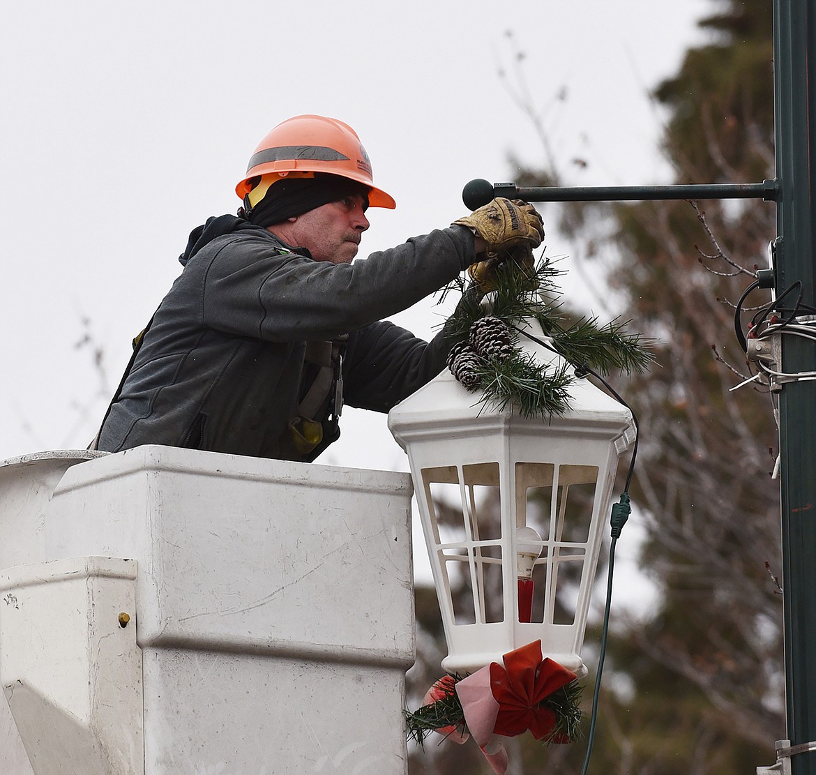 Volunteers hang the winter decorations downtown Sunday morning. Among those assisting are a crew from Flathead Electric Co-op. (Heidi Desch/Whitefish Pilot)