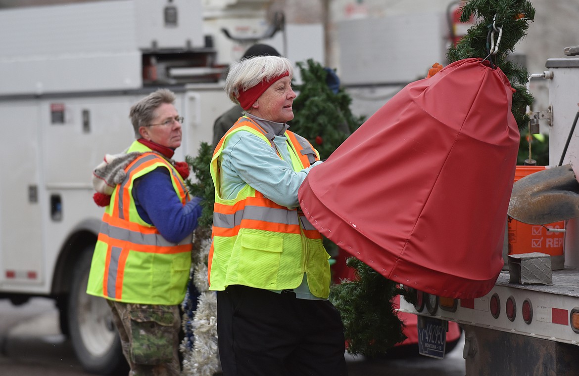 Volunteers hang the winter decorations downtown Sunday morning. (Heidi Desch/Whitefish Pilot)