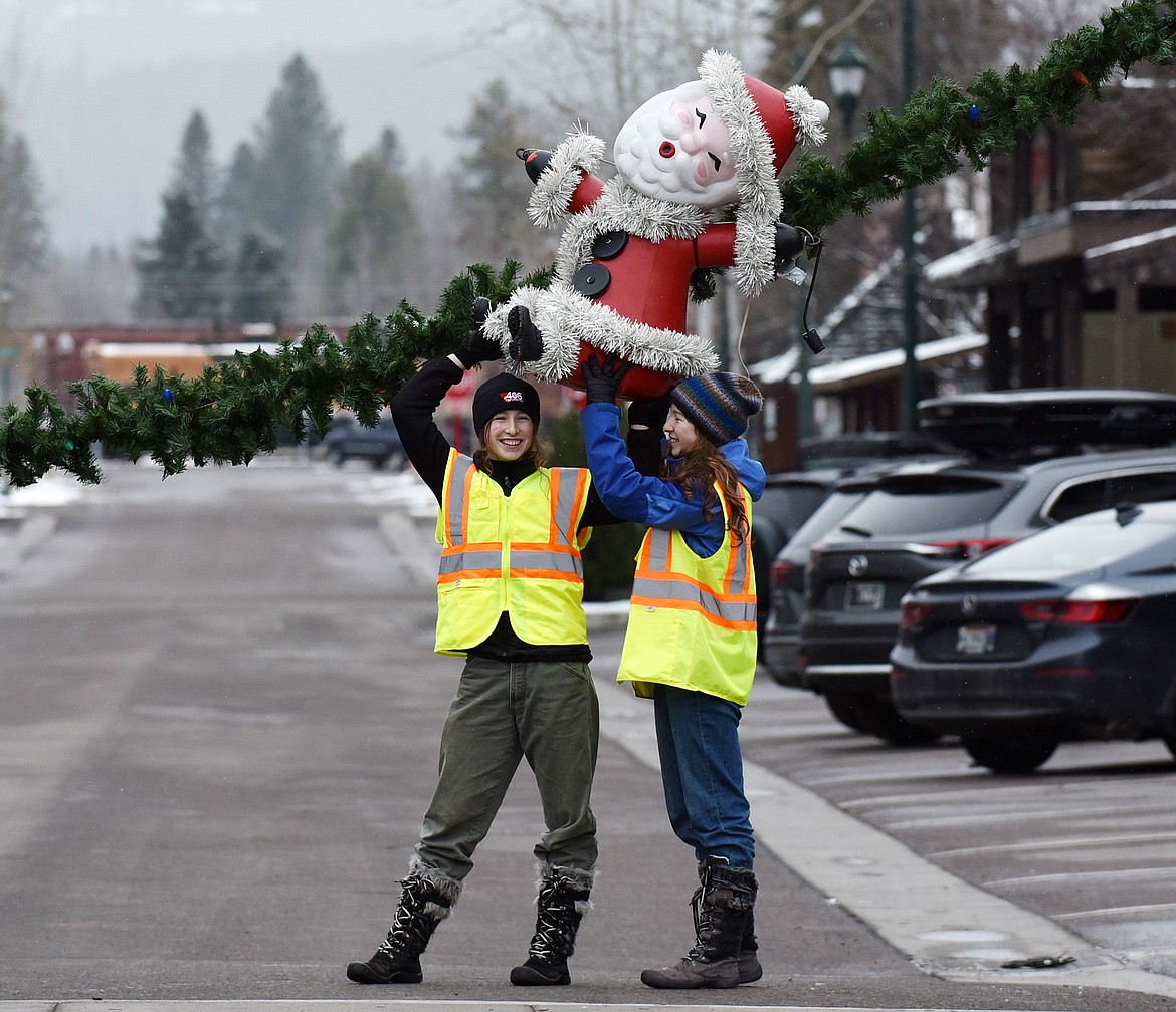 Volunteers hang the winter decorations downtown Sunday morning. (Heidi Desch/Whitefish Pilot)