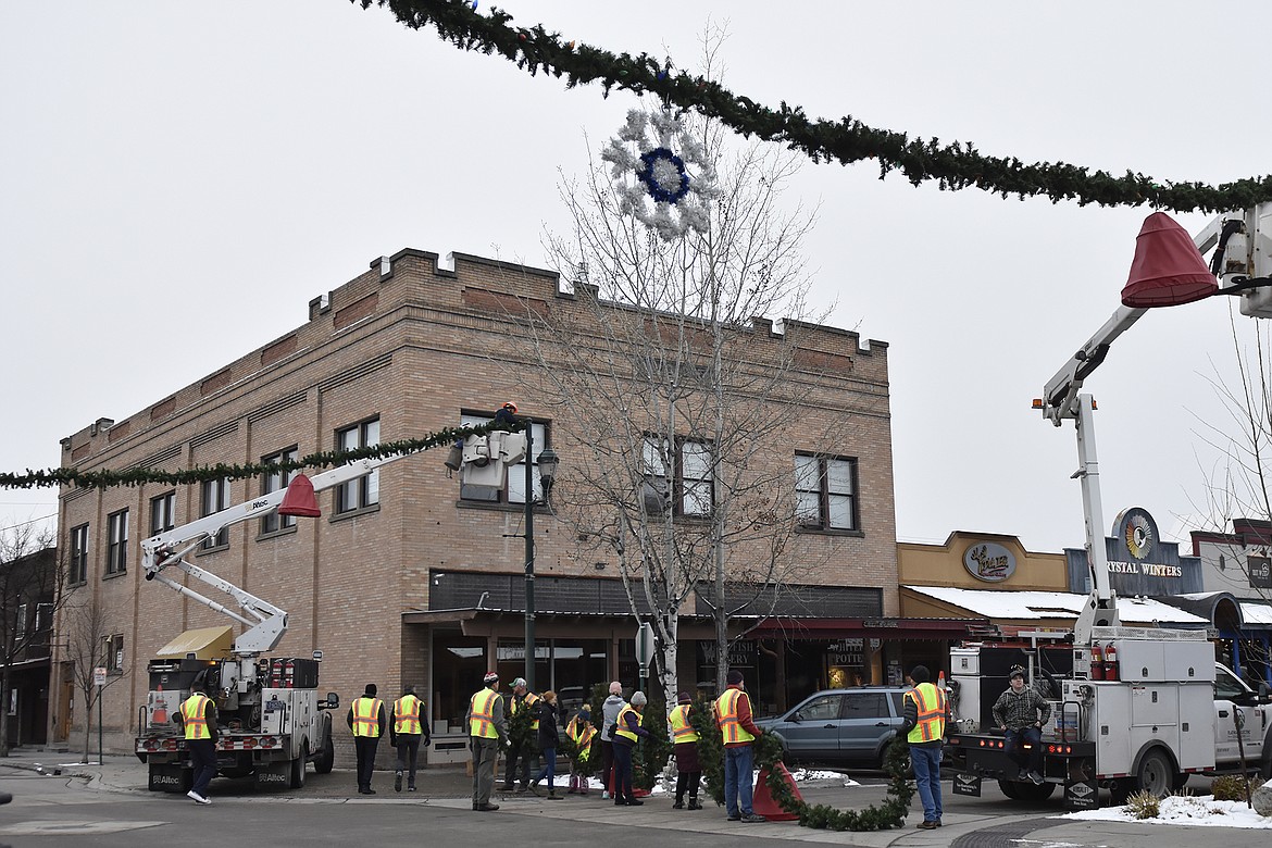 Volunteers hang the winter decorations downtown Sunday morning. (Heidi Desch/Whitefish Pilot)