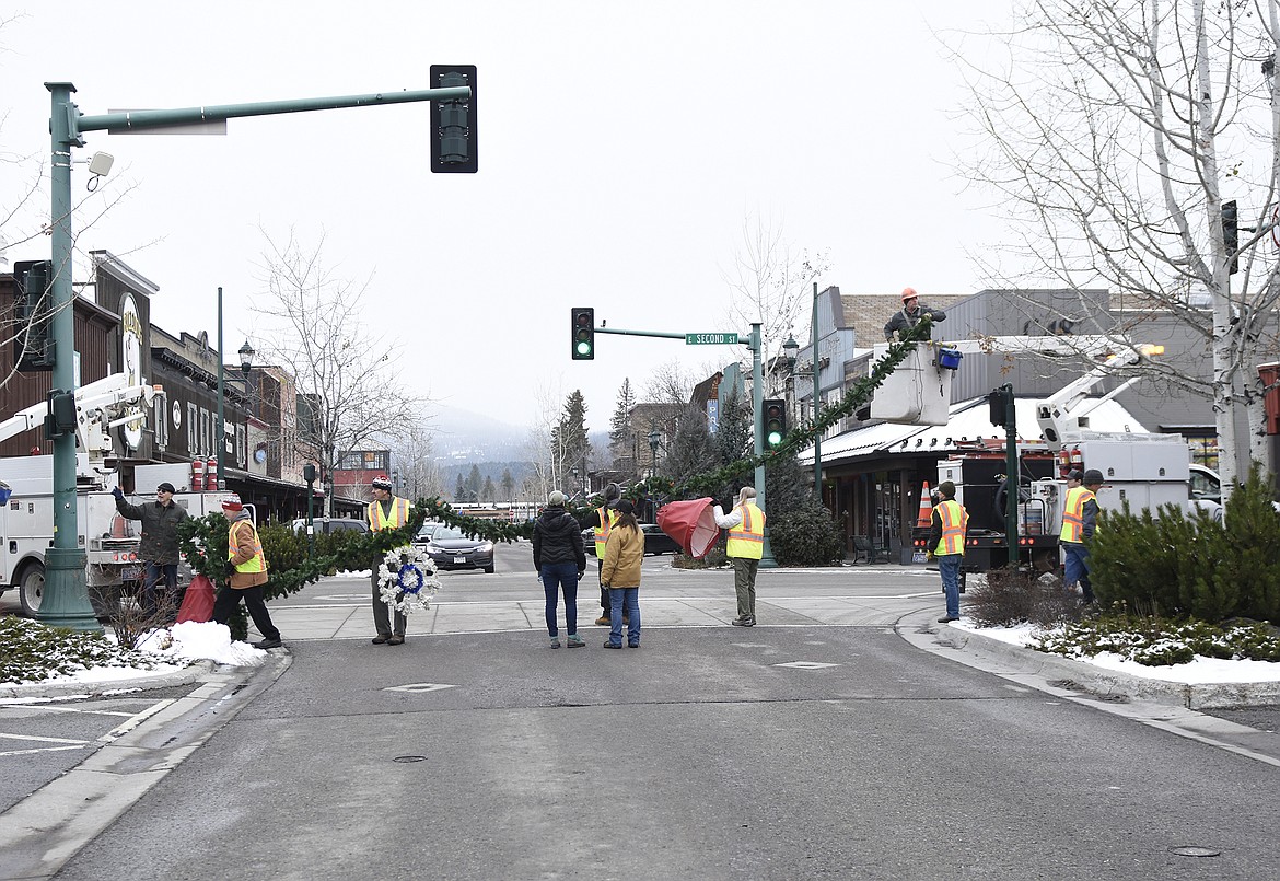 Volunteers hang the winter decorations downtown Sunday morning. (Heidi Desch/Whitefish Pilot)