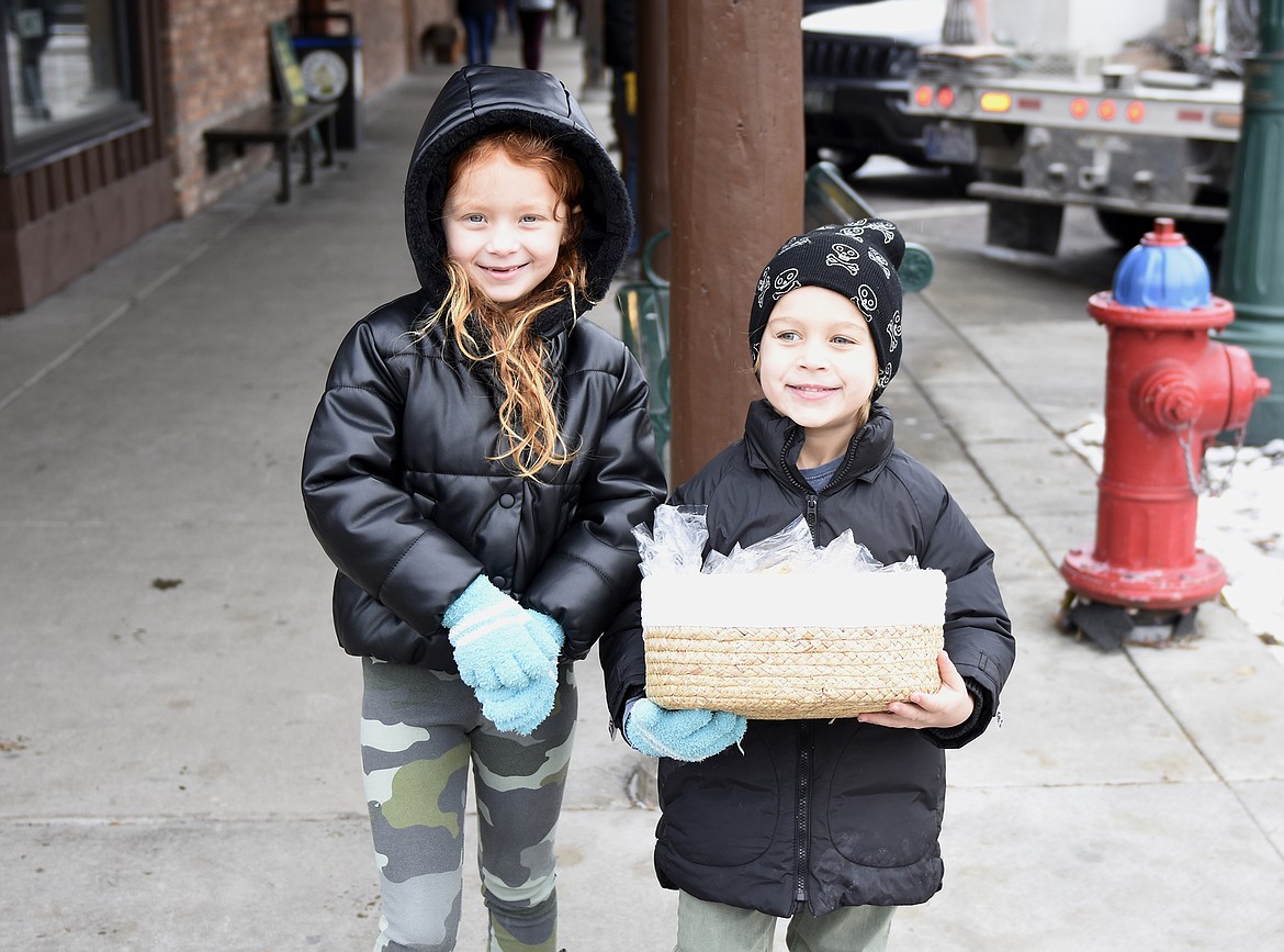 Ayva Orr, 7, and Theo Orr, 5, delivered cookies to volunteers hanging the winter decorations downtown on Sunday morning. (Heidi Desch/Whitefish Pilot)