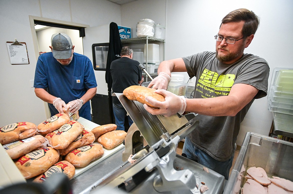 From left, volunteers Monty McIlhargey, Phil Anderson and Erik Anderson slice turkey in preparation for the Thanksgiving dinner at Syke's Diner on Tuesday, Nov. 23. (Casey Kreider/Daily Inter Lake)