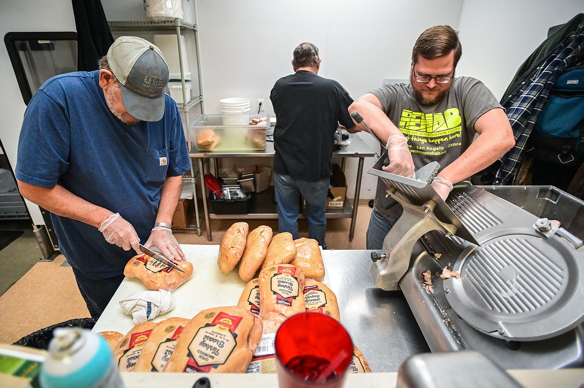 From left, volunteers Monty McIlhargey, Phil Anderson and Erik Anderson slice turkey in preparation for the Thanksgiving dinner at Syke's Diner on Tuesday, Nov. 23. (Casey Kreider/Daily Inter Lake)