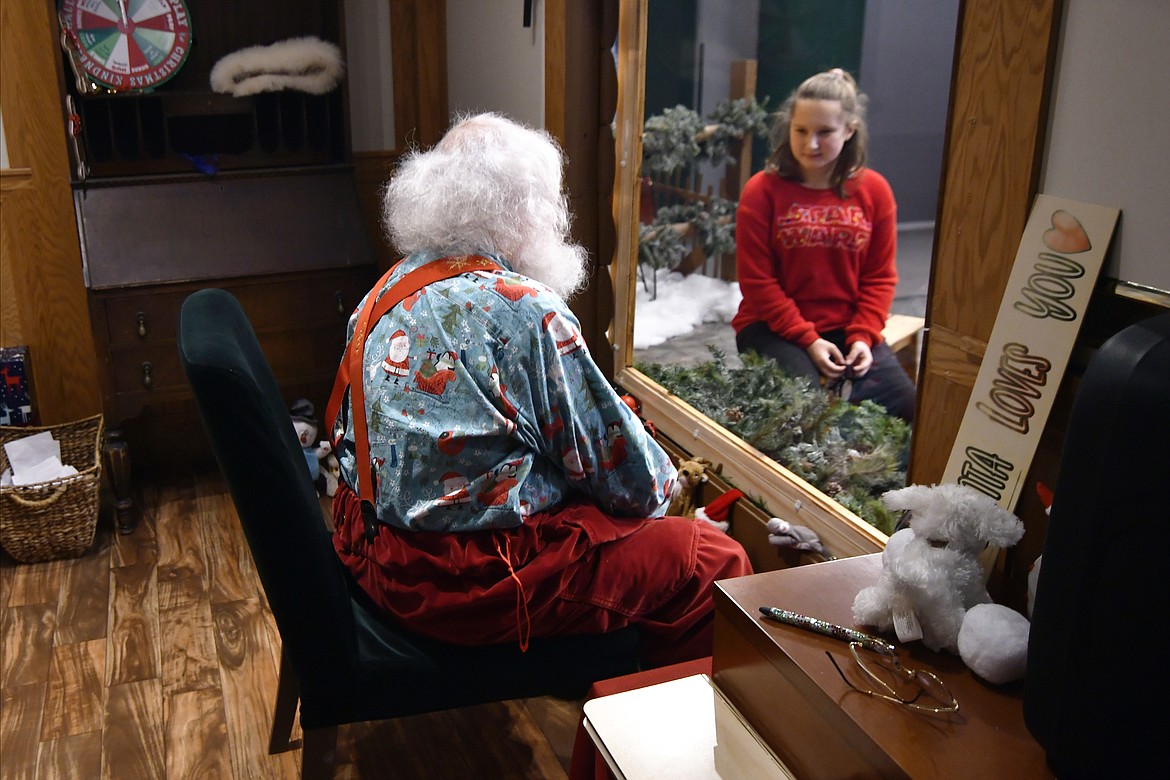 anta, Sid Fletcher, sits behind glass as he gets a Christmas wish list from Kendra Alexander of St. James, Minn., during her visit Monday, Nov. 15, 2021, at The Santa Experience in the Mall of America in Bloomington, Minn. Where allowed, some malls and big-box stores are offering Santa's guests a choice of full contact or social distance. (AP Photo/Jim Mone)