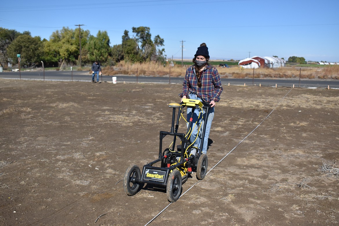 Maria Kovach pushes the ground-penetrating radar across the dirt to help evaluate the cemetery on Oct. 10.