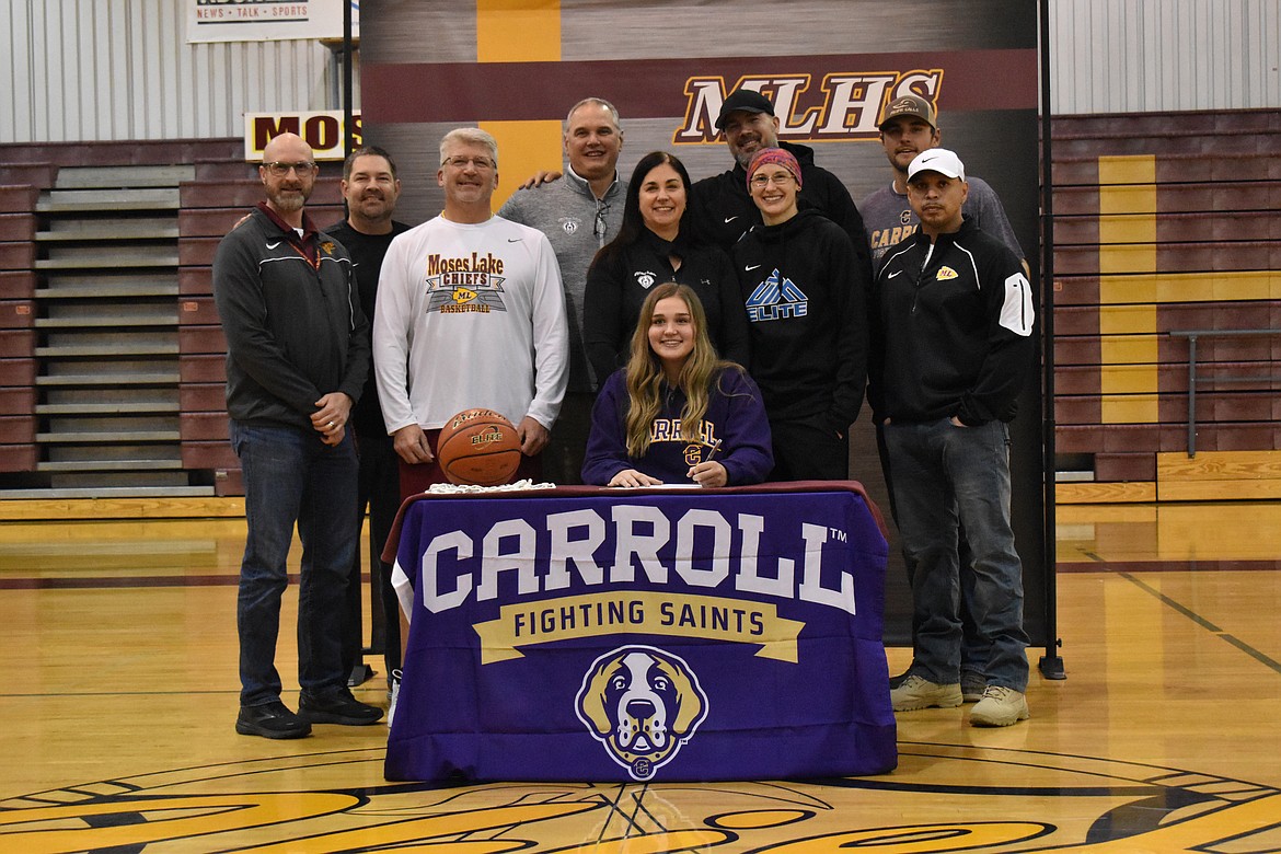 Meagan Karstetter, seated, signs her letter of intent with Carroll College on Tuesday. With her, from left, are Moses Lake High School assistant athletic director Clint Scriven, former coach Brant Mayo, MLHS head girls basketball coach Matt Strophy, parents Tom and Michelle Karstetter, Kalen and Katelan Stroyan of Unique You Fitness Basketball Coaching in Spokane, brother Tyson Karstetter and South Campus Athletic Club athletic trainer Hector Cuello.
