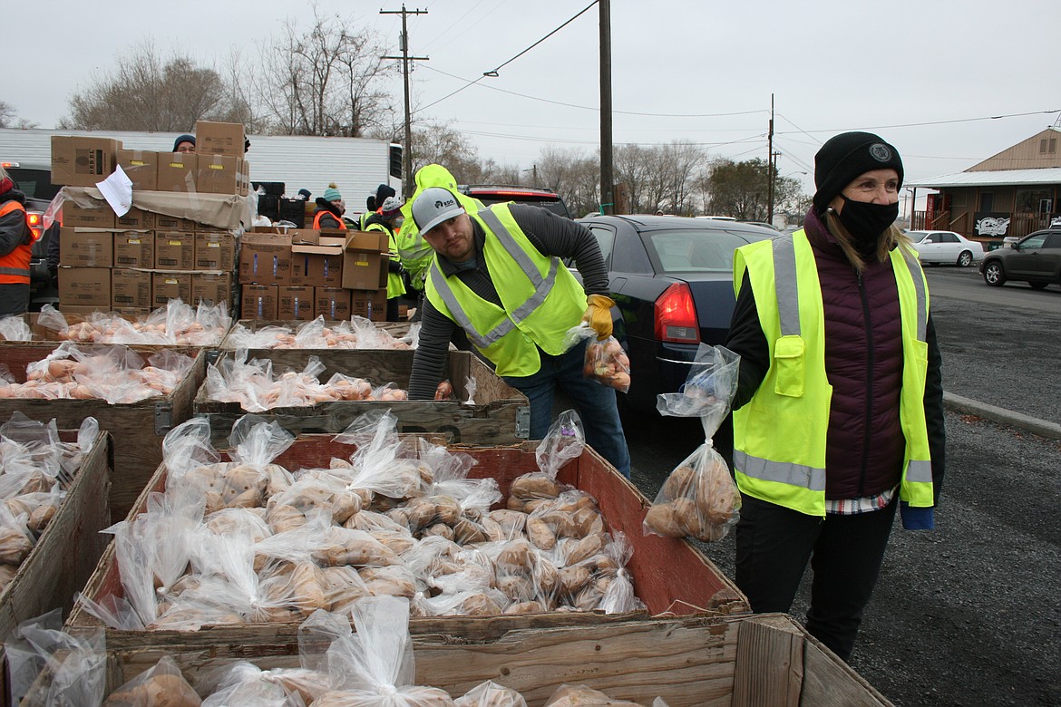 David Anderson picks up a bag of onions to put in the car of a Moses Lake Food Bank customer during the food bank’s Thanksgiving distribution drive-thru Monday.