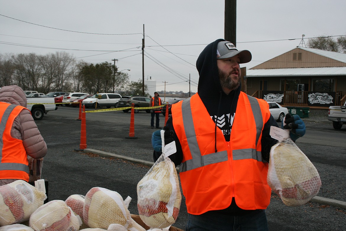 Volunteer Barry Sterner distributes turkeys in the drive-thru at the Moses Lake Food Bank Monday.