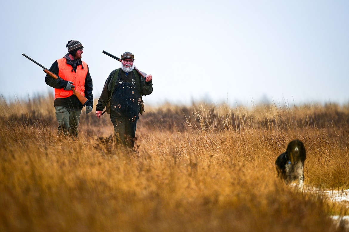 Kyle Kivela, left, and Scott Roberts head back to their vehicle with Finny, a springer spaniel, after hunting for pheasants at the Blasdel Waterfowl Production Area on Friday, Nov. 19. (Casey Kreider/Daily Inter Lake)