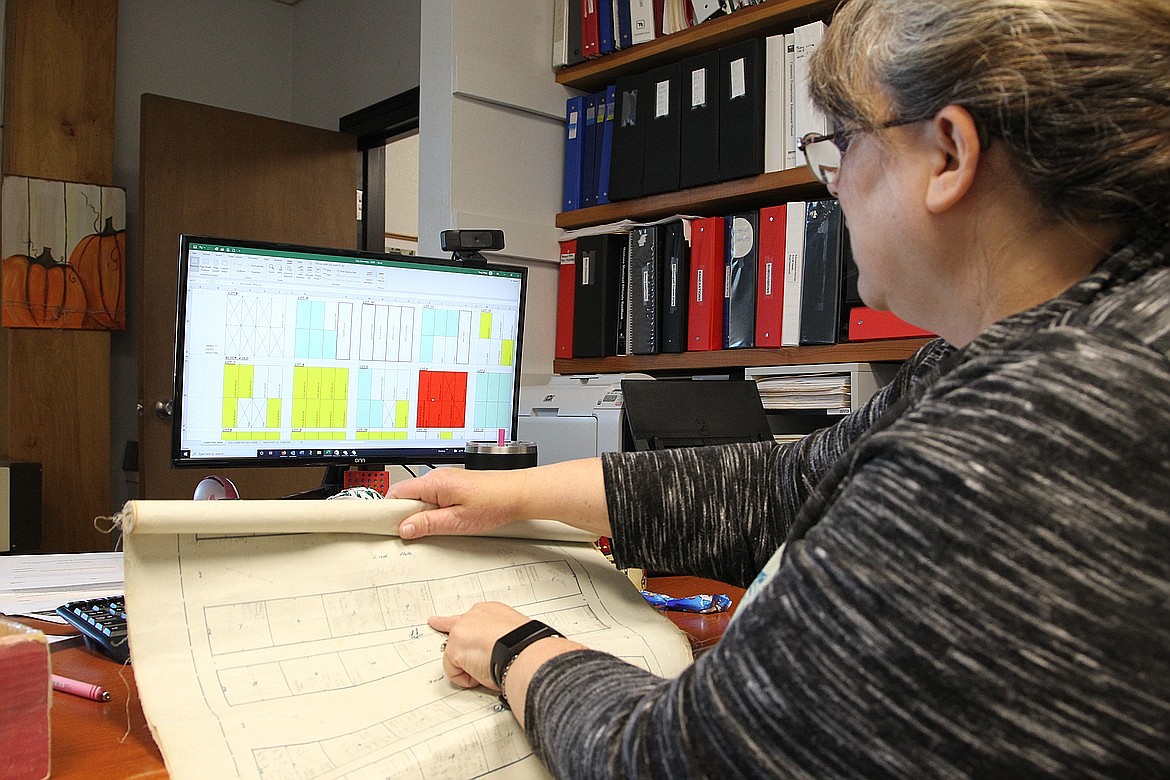 Tracy Rebo, Troy city clerk and treasurer, matches plots in the Troy City Cemetery Plat with a digitized map of the cemetery. (Will Langhorne/The Western News)