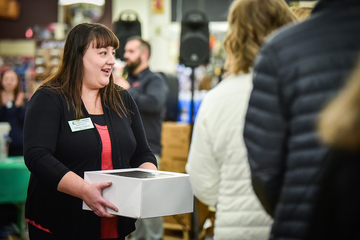 Kristina Mahan, an ambassador with the Evergreen Chamber of Commerce, shows off one of the pies during the live auction at Light Up Evergreen & Pie Auction at The Hardware Store on Tuesday, Nov. 23. (Casey Kreider/Daily Inter Lake)