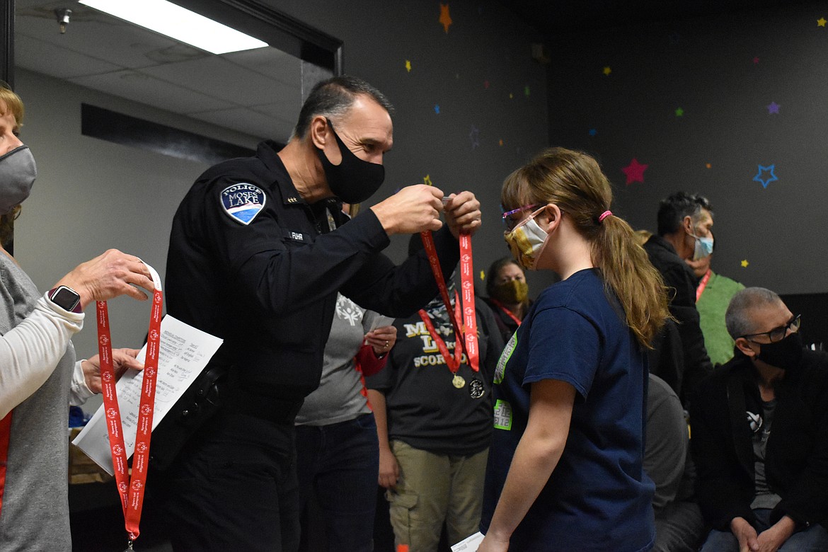 Moses Lake Police Department Chief Kevin Fuhr places a silver medal on Karissa Reed, who won the silver medal in the individual category in bowling.