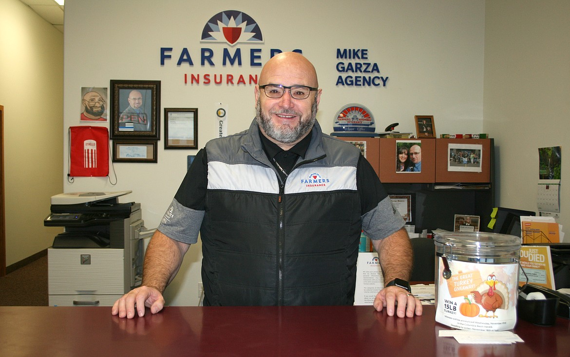 Mike Garza stands at the counter of his insurance agency. Garza now owns his own business after starting his working life in the fields.