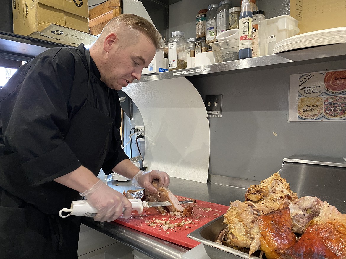 Wayne Morgan, general manager of The Gateway Cafe in Plummer, was overjoyed after hearing the restaurant had quickly away more than 60 Thanksgiving meals on Thursday. Here, Morgan carves up some turkey for the next round of to-go orders. (MADISON HARDY/Press)