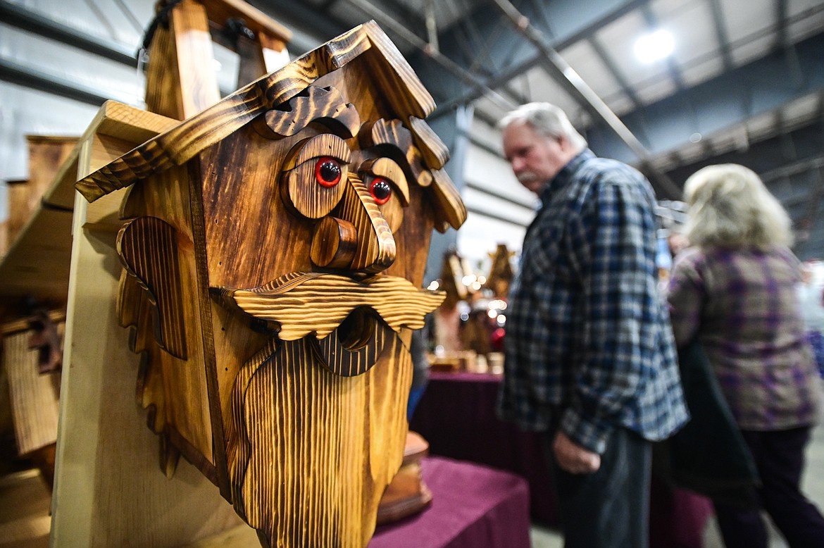 Shoppers browse at a stand of bird feeders and other wooden creations at the Hand Crafted by Ed Meuli stand at the Artists and Craftsmen of the Flathead's 40th annual Christmas show at the Flathead County Fairgrounds on Friday, Nov. 26. (Casey Kreider/Daily Inter Lake)