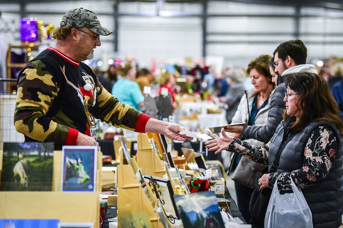 Customers shop at the Craig Solin Photography stand at the Artists and Craftsmen of the Flathead's 40th annual Christmas show at the Flathead County Fairgrounds on Friday, Nov. 26. (Casey Kreider/Daily Inter Lake)