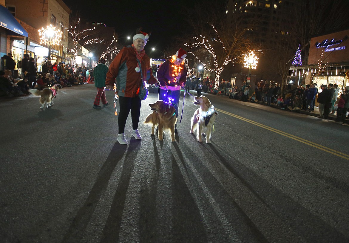 Carol Cook, left, with Maggie, and Sharon Philliber with Molly, walk with the rest of the Coeur d'Alene Dog Fanciers in the 29th annual Lighting Ceremony Parade Friday night on Sherman Avenue.