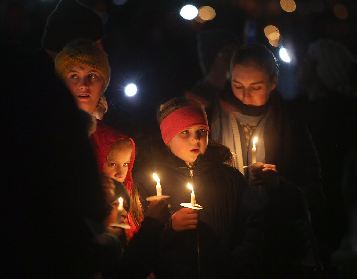 People hold candles and sing "Silent Night" at The Coeur d'Alene Resort's lighting ceremony Friday night. From left, Katy, Brianna, Stephanie and Lizzie Salmeri.