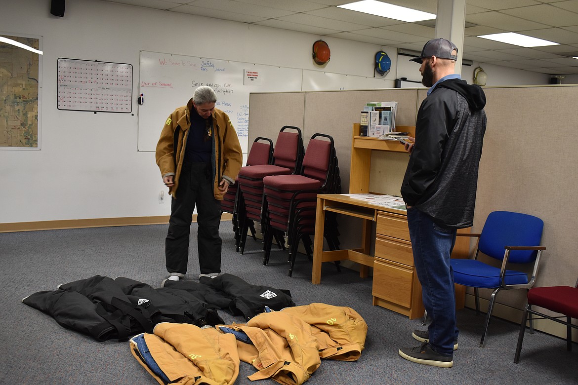 Grant County Fire District 7 volunteer Jane Chambers tries on different sizes of bunker gear so Adam Sitton, at right, the vendor ordering custom bunker gear, can get her the right size.