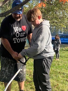 Volunteers of "We Love Our Town" community outreach program teaching youth in the community how to use a weedwacker.