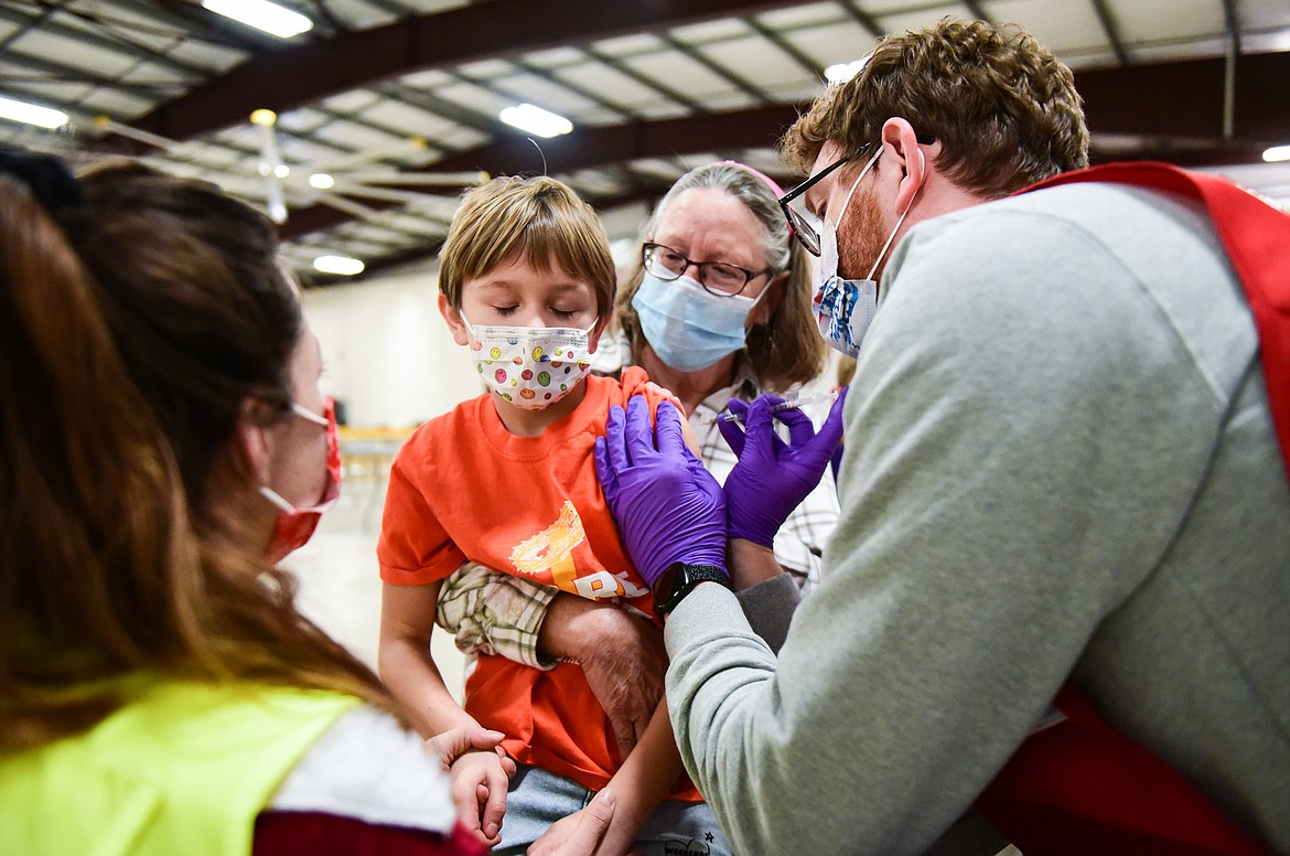 Ember Reed, 6, closes her eyes as she is administered a Pfizer Covid-19 vaccine with her grandmother and guardian Aggie (back) during a clinic for children ages 5-11 at the Flathead County Fairgrounds in Kalispell on Wednesday, Dec. 1. (Casey Kreider/Daily Inter Lake)